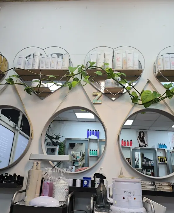 Circular salon mirrors, professional products and trailing plants at Naz Hair and Beauty