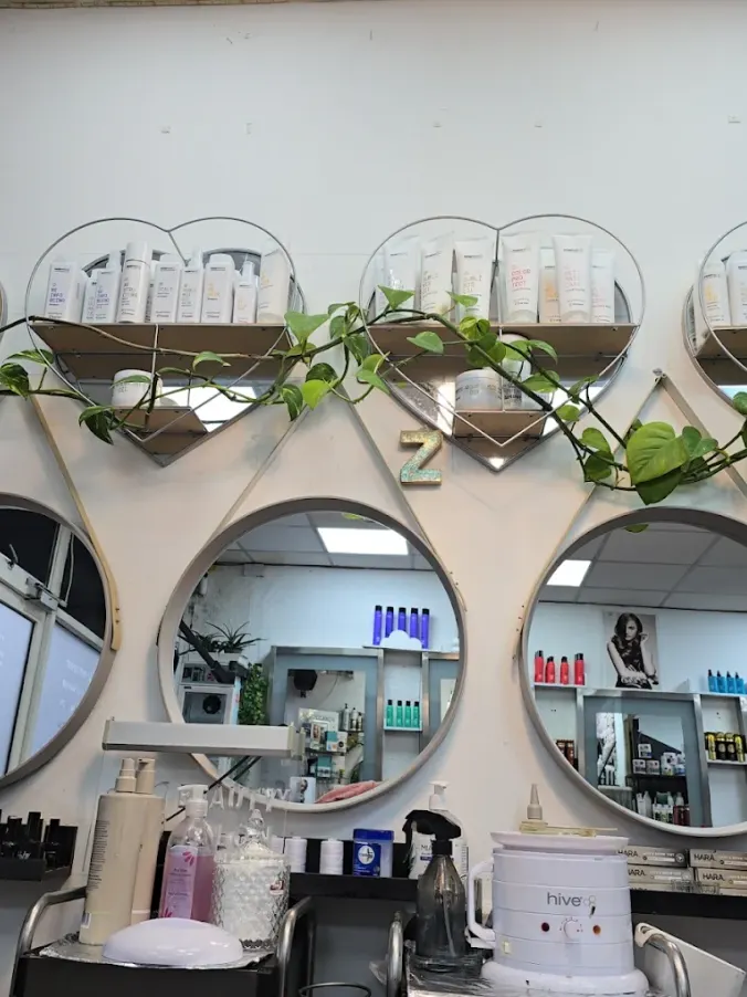 Circular salon mirrors, professional products and trailing plants at Naz Hair and Beauty